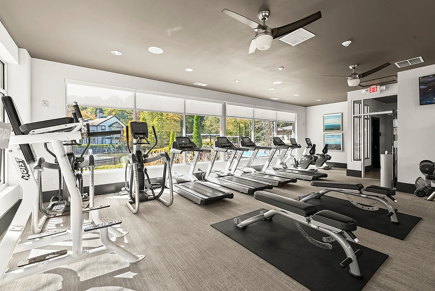 Bright and modern fitness center with treadmills and exercise machines overlooking scenic outdoor views.