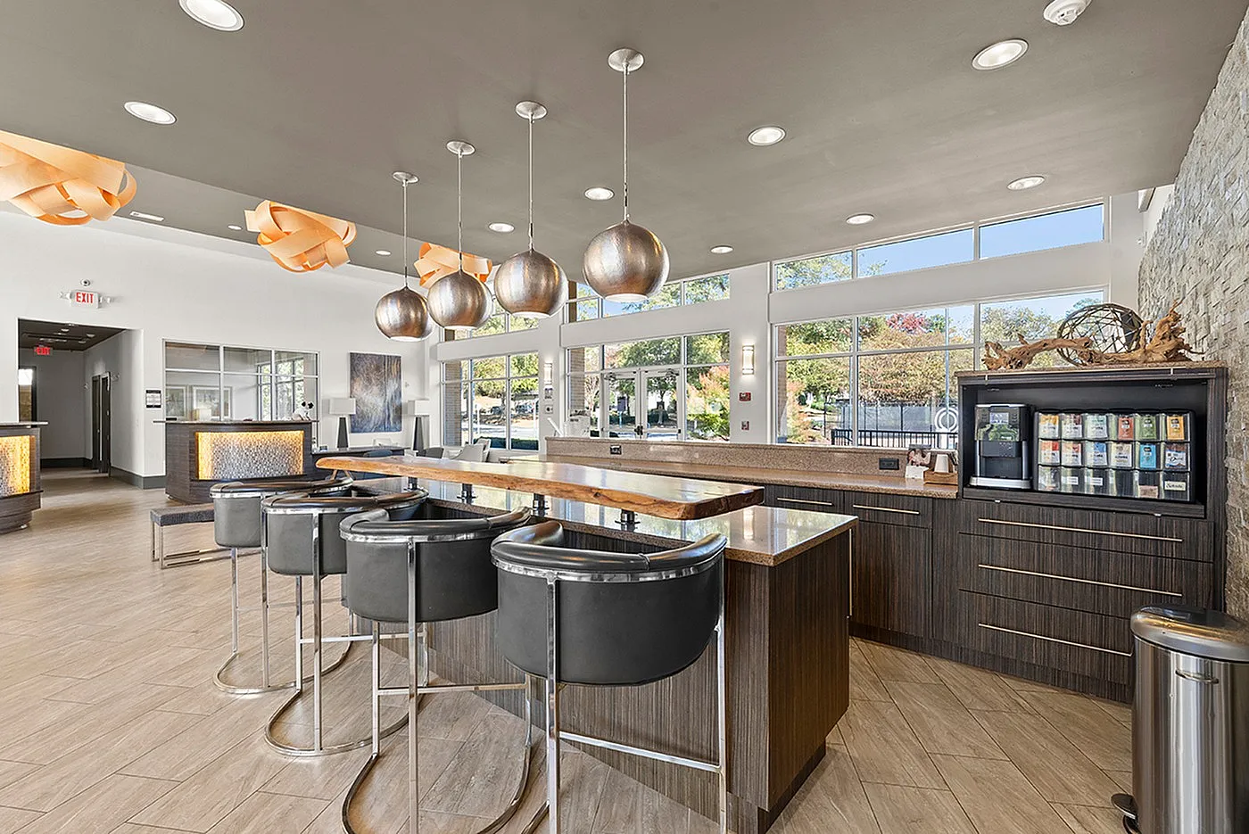 Luxurious modern lounge featuring sleek bar seating, stylish pendant lights, and panoramic windows with natural views.