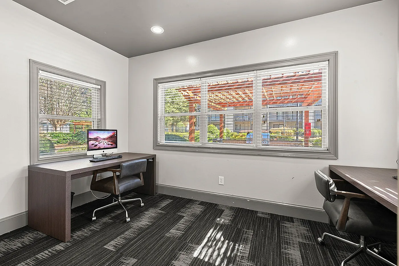 Bright home office space with modern desk, ergonomic chair, and large windows offering scenic outdoor views.
