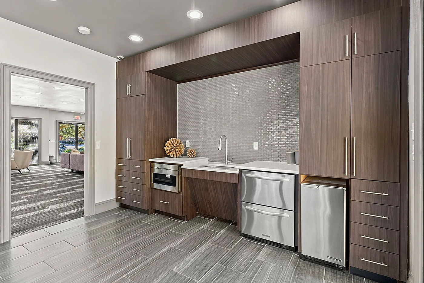 Contemporary kitchen with sleek dark wood cabinetry, stainless steel appliances, and modern tile flooring, opening onto a stylish living area with ample natural light.