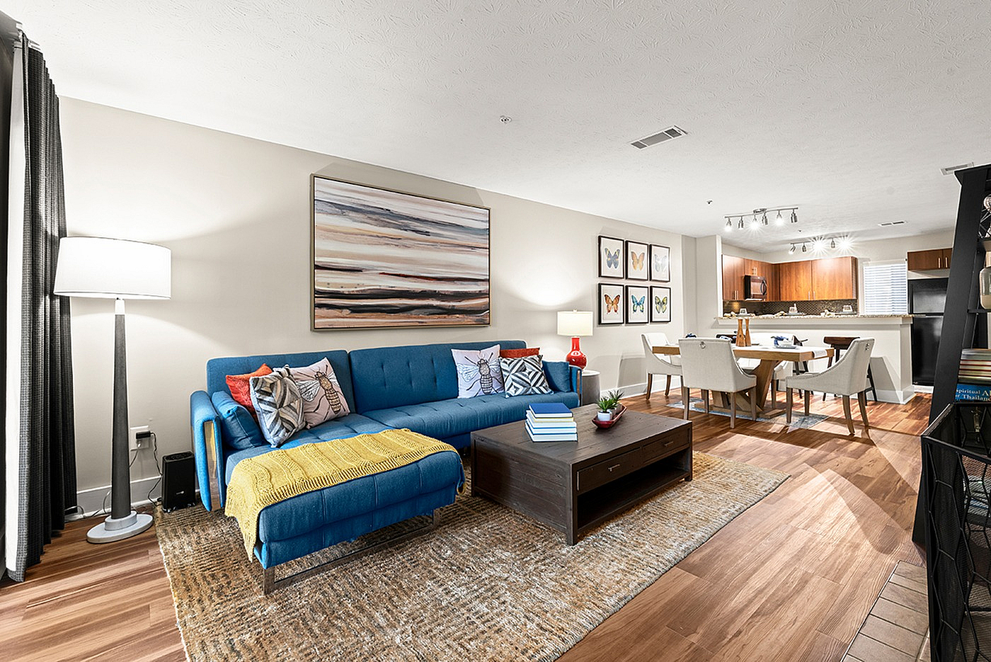 Inviting open-concept living space with a cozy blue sofa, vibrant artwork, and a modern dining area, perfect for stylish living and entertaining.