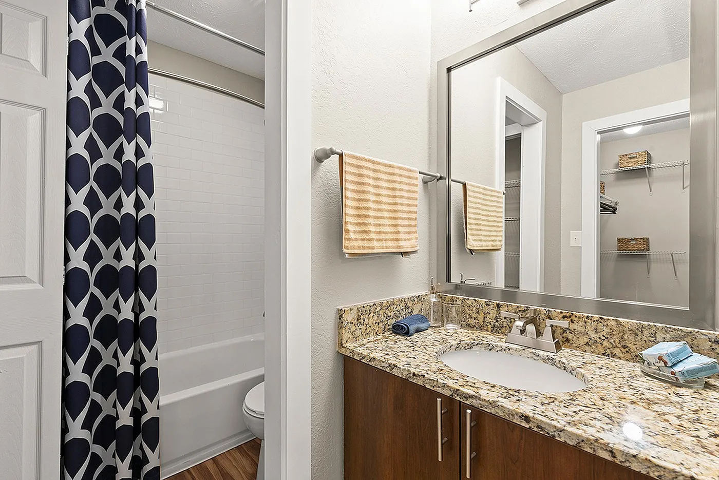 Chic bathroom featuring a granite countertop, modern fixtures, and a stylish navy patterned shower curtain.