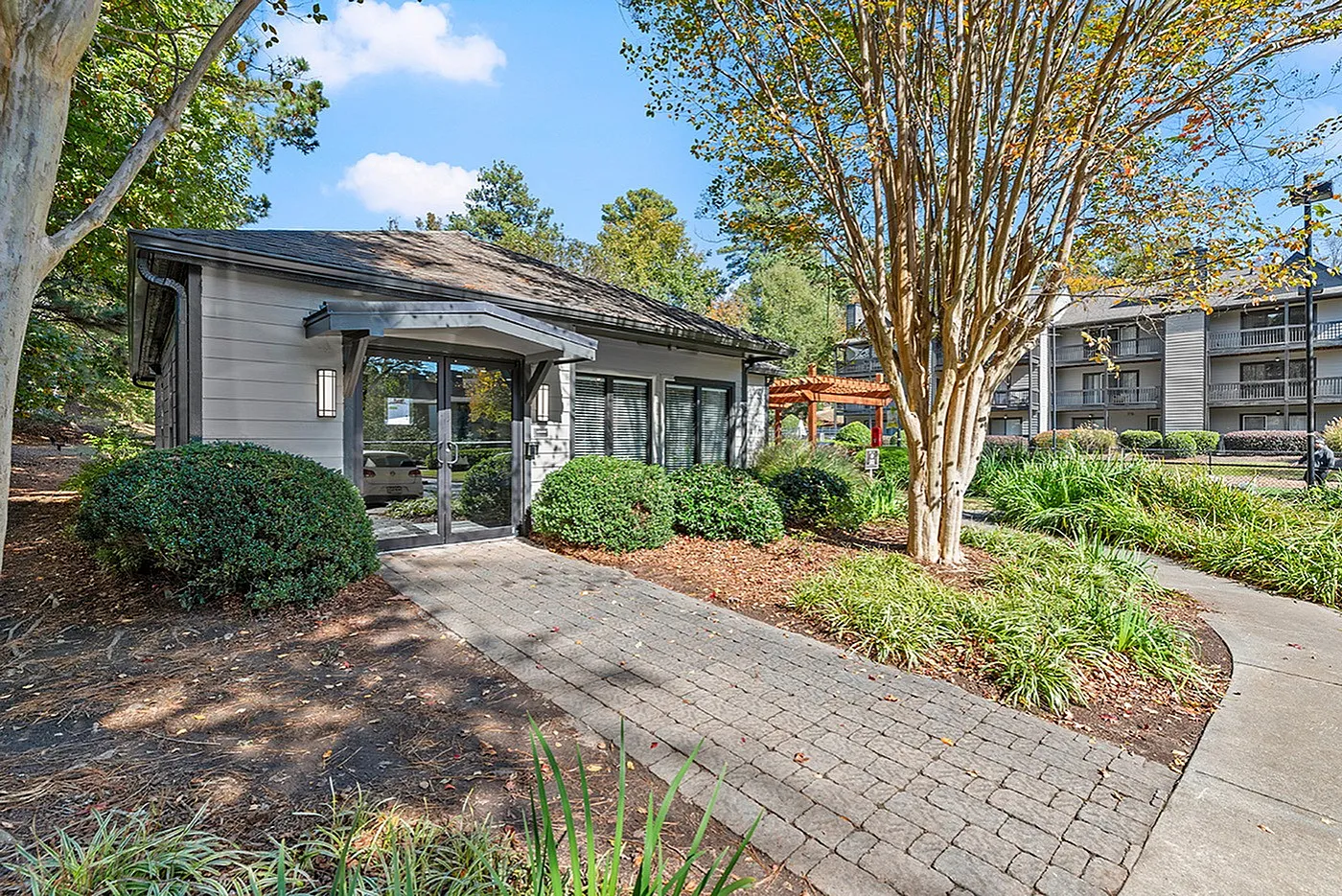 Charming residential building surrounded by lush greenery and a picturesque pathway, creating a serene and welcoming atmosphere.