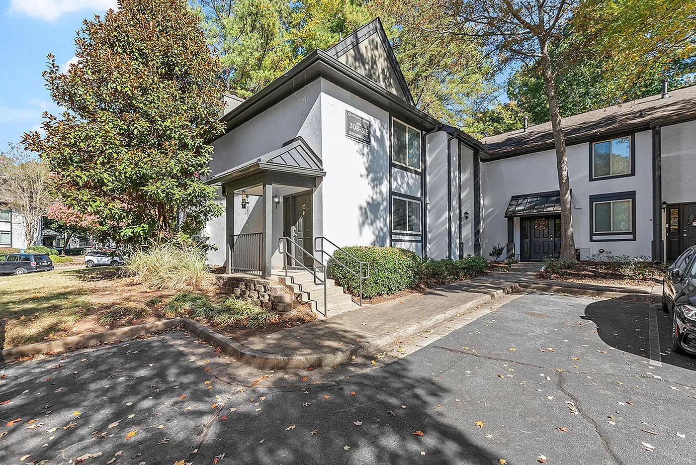 Charming townhouse with modern architecture, surrounded by lush greenery and ample parking space, set in a serene neighborhood.