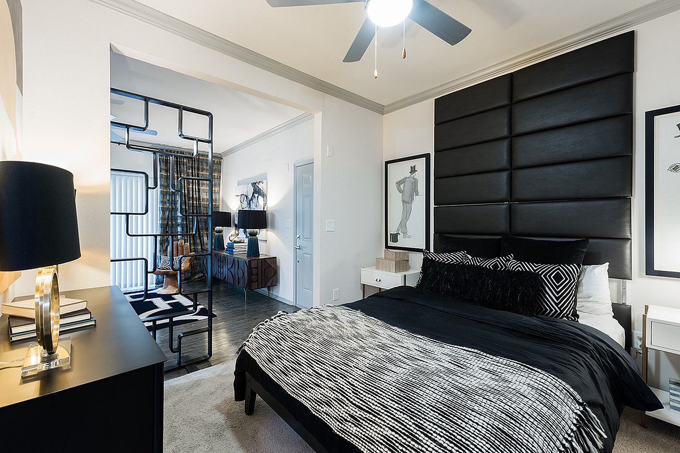 Modern bedroom featuring elegant black and white decor, stylish art, and a unique partition in a chic apartment setting.