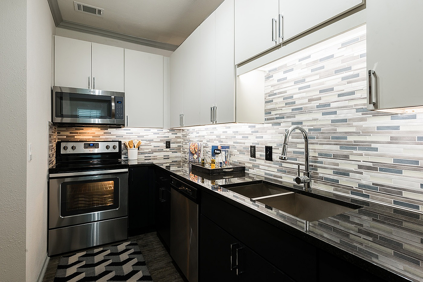 Modern kitchen with sleek stainless steel appliances, stylish mosaic tile backsplash, and dark granite countertops.