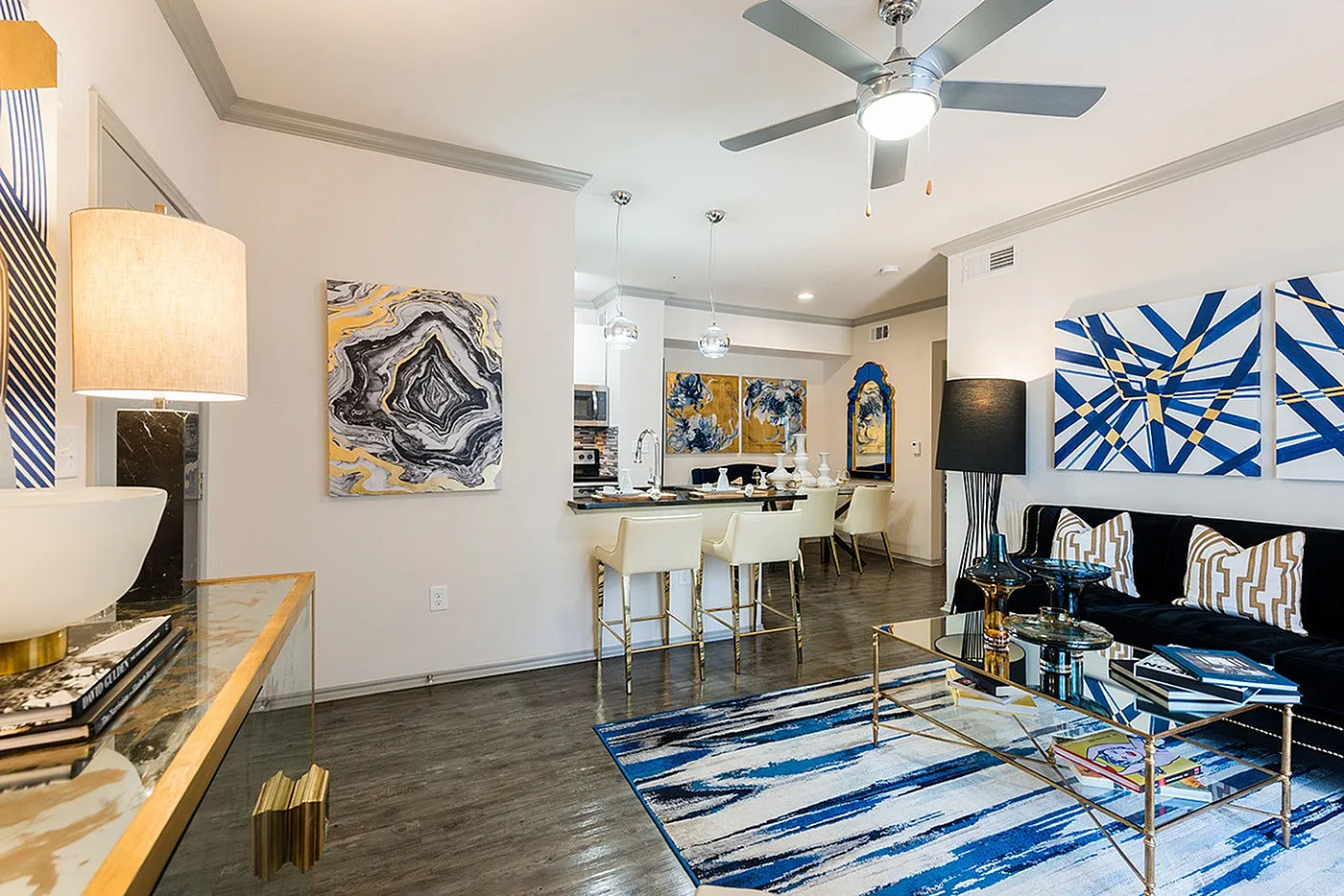 Contemporary open-plan living room with stylish decor, featuring vibrant abstract artwork, modern furnishings, and a sleek dining area adorned with elegant lighting.