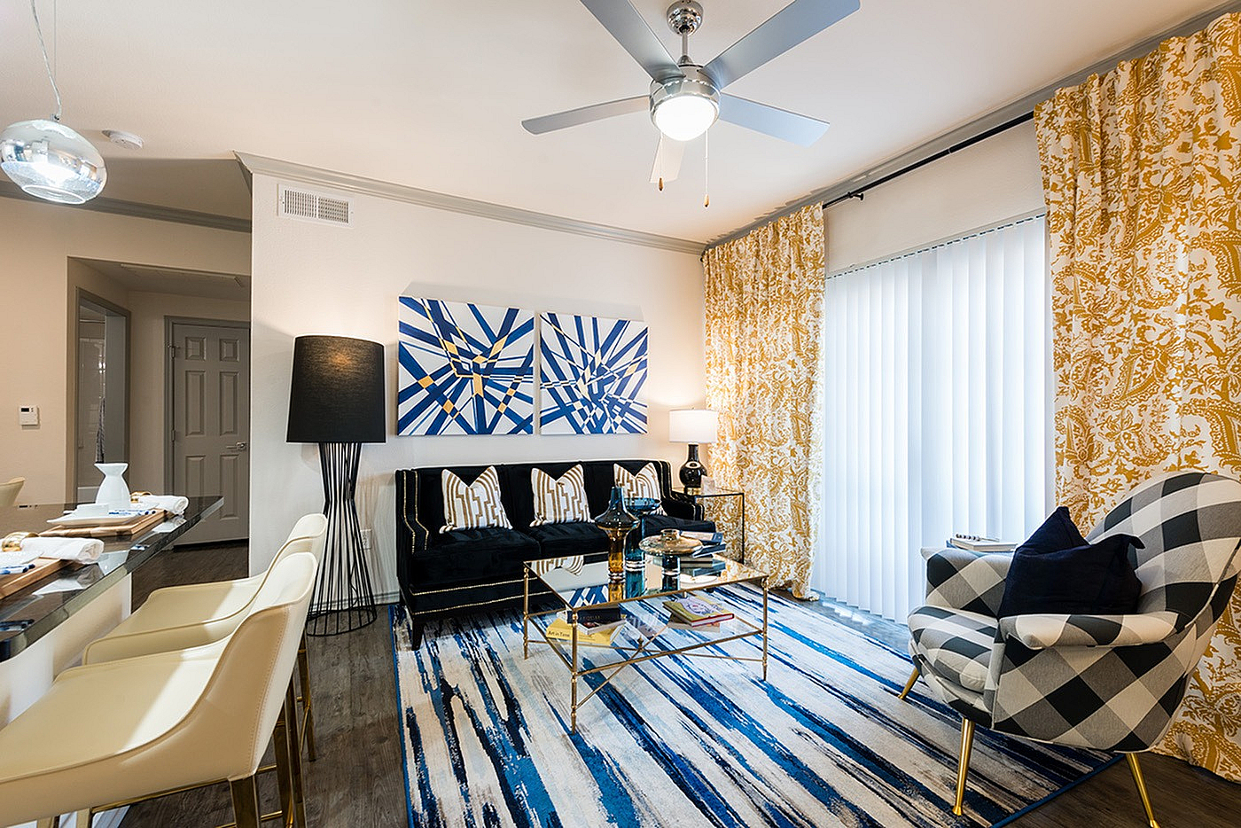 Chic living room with modern art, plush black sofa, and bold patterned decor, offering a blend of elegance and comfort.