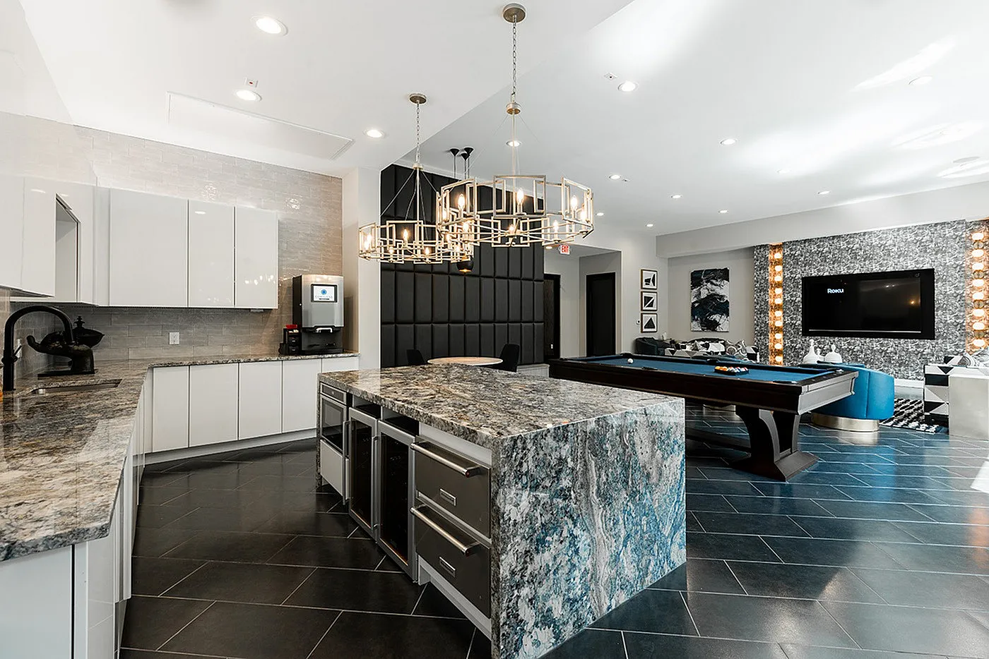 Luxurious apartment interior showcasing a sleek modern kitchen with elegant marble countertops, chic lighting, and an inviting entertainment area with a billiards table and stylish lounge seating.