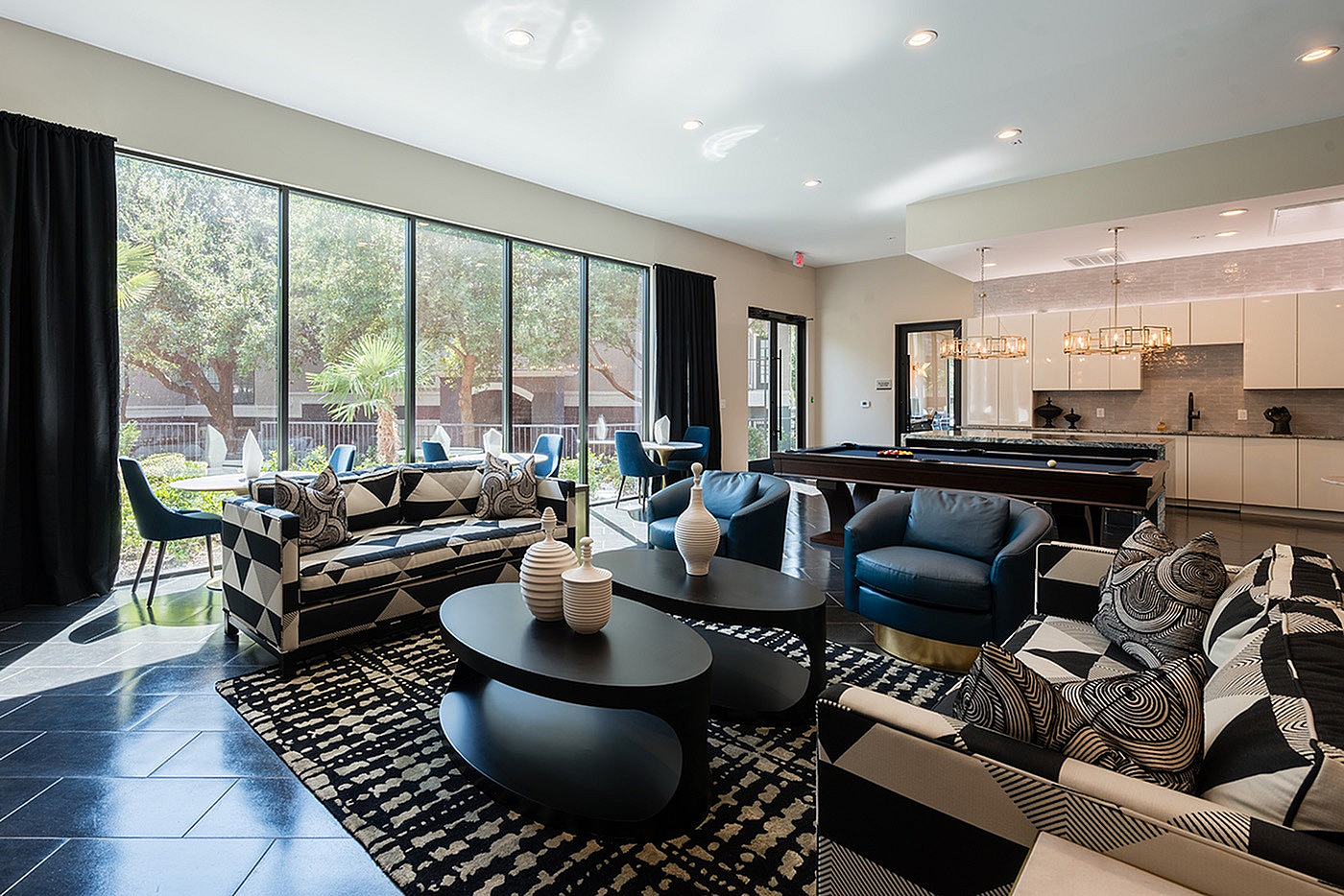 Luxurious open-concept living room with modern decor, featuring large windows, stylish seating, and a sleek kitchen space.