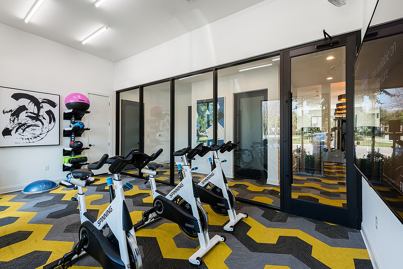 Modern fitness room featuring sleek spinning bikes and vibrant geometric flooring, perfect for invigorating workouts.