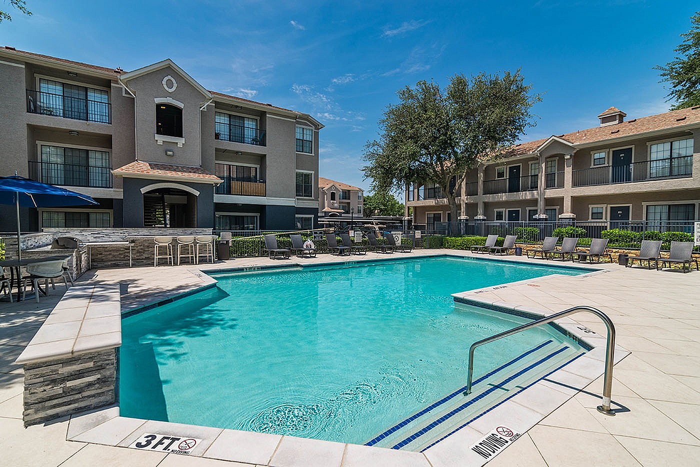 Charming apartment complex with a sparkling swimming pool, sun loungers, and lush greenery, perfect for relaxation and leisure.