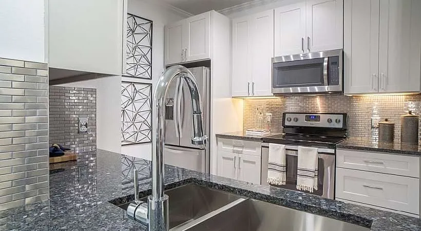 Modern kitchen with sleek stainless steel appliances, elegant granite countertops, and a stylish tile backsplash.