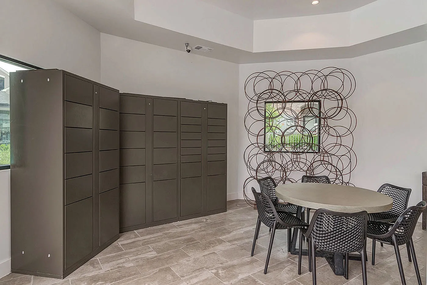 Modern communal room with round table, artistic wall decor, and sleek storage cabinets, exuding a contemporary vibe.