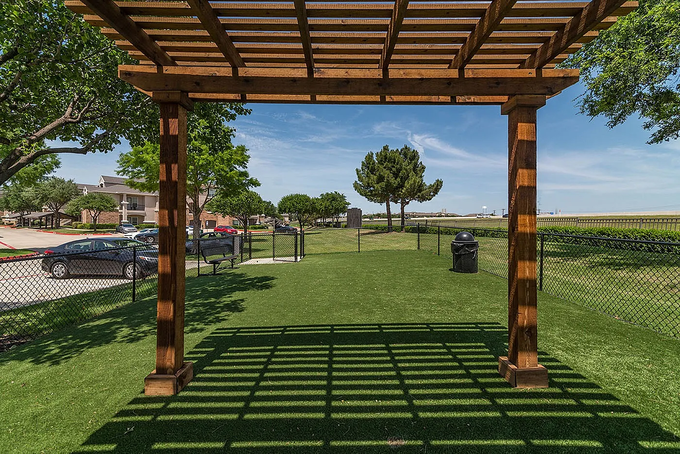 Charming outdoor space featuring a wooden pergola, lush green lawns, and serene surroundings perfect for relaxation.