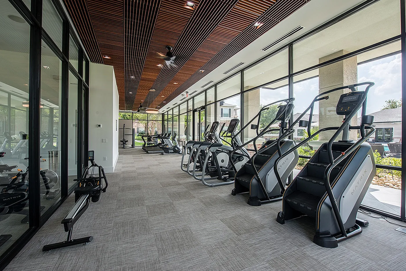 Sleek and modern fitness center with state-of-the-art cardio equipment, offering a bright and spacious workout environment with large windows.