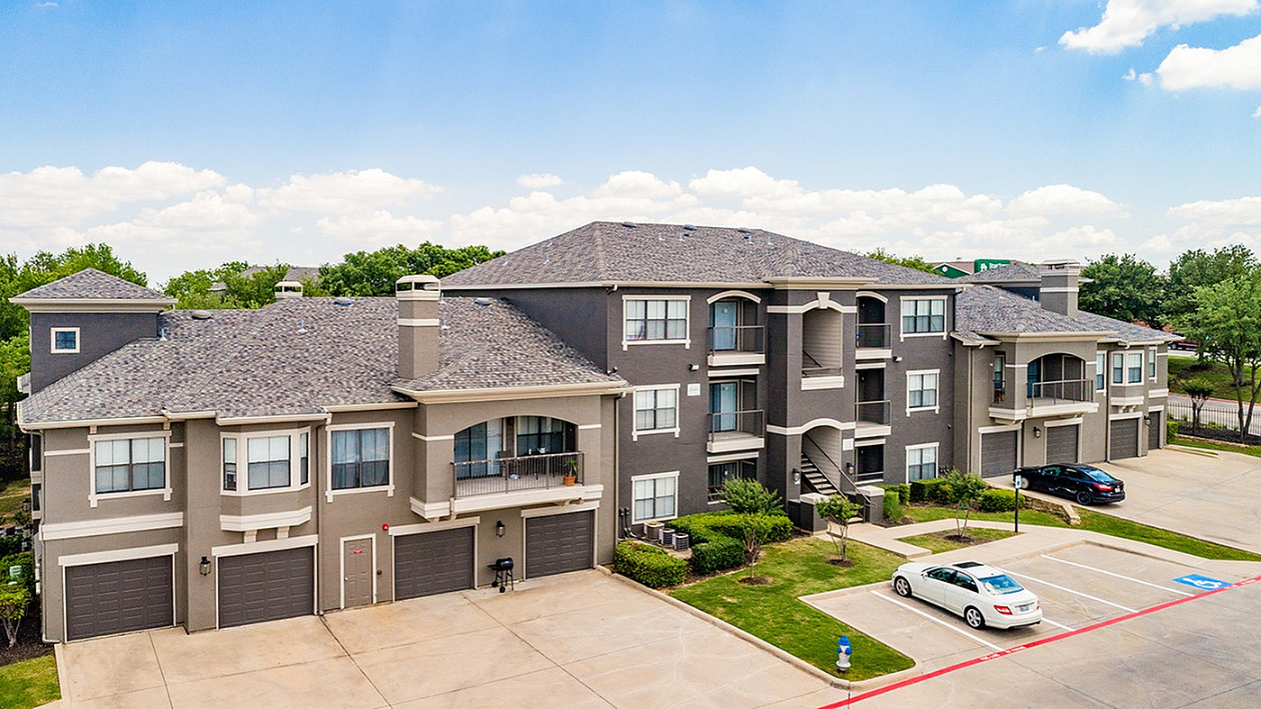 Elegant apartment complex with modern architecture, featuring spacious balconies and convenient parking, set against a scenic backdrop of lush greenery.