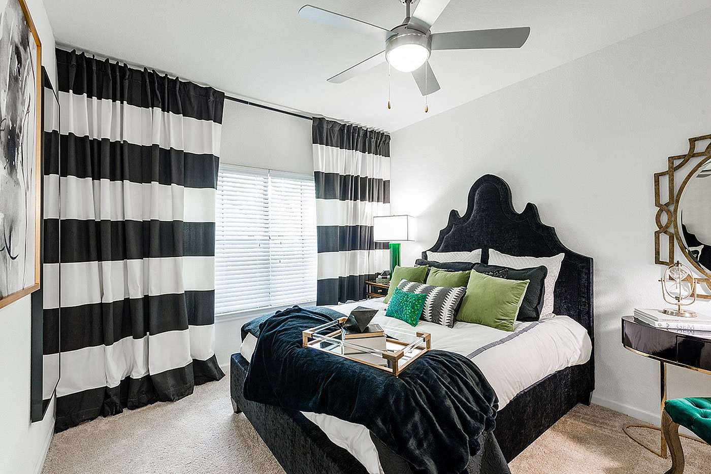Chic bedroom with elegant decor, featuring a plush velvet bed, stylish black-and-white curtains, and modern accessories.