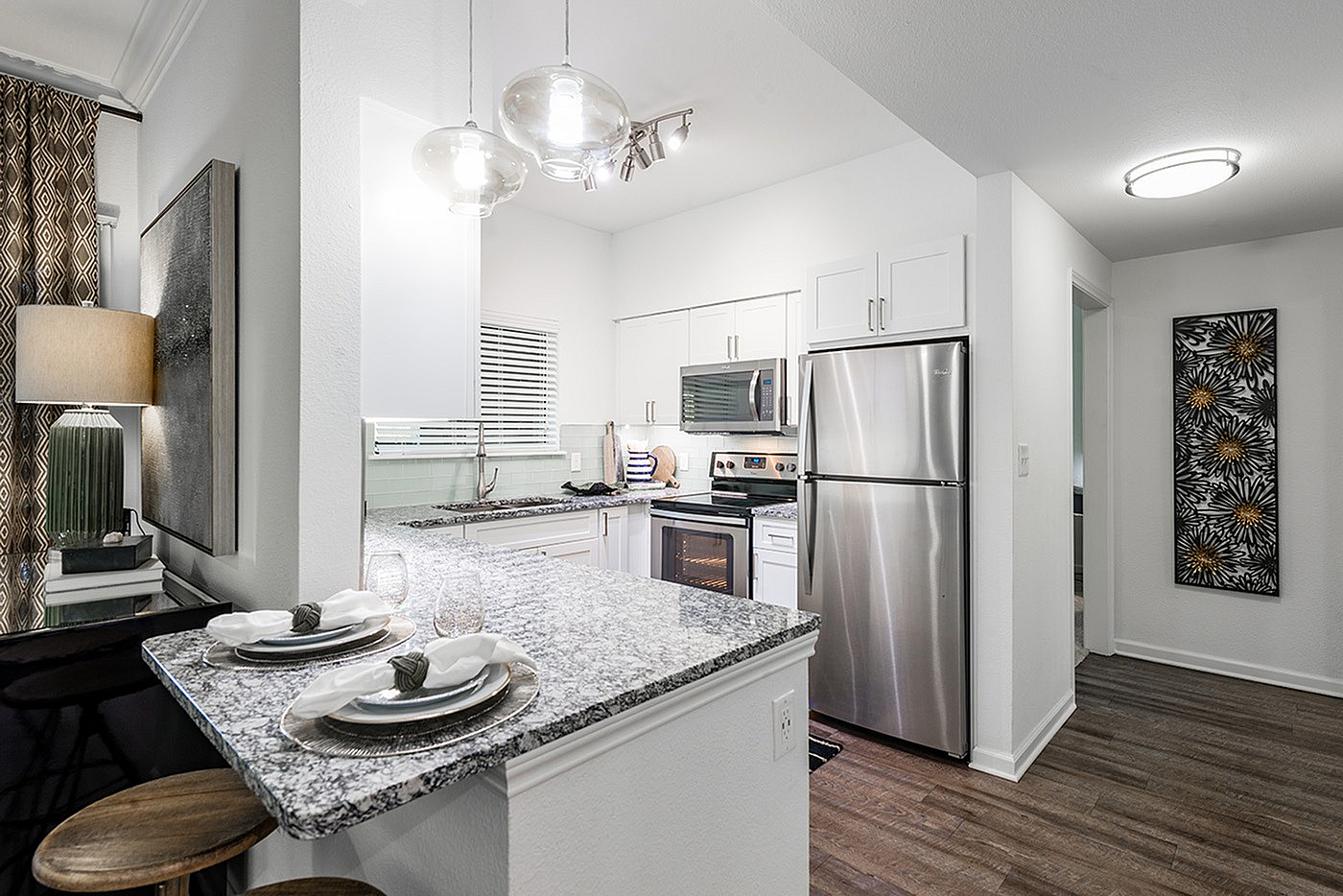 Modern kitchen with granite countertops, sleek stainless steel appliances, and chic pendant lighting, offering an inviting open layout.
