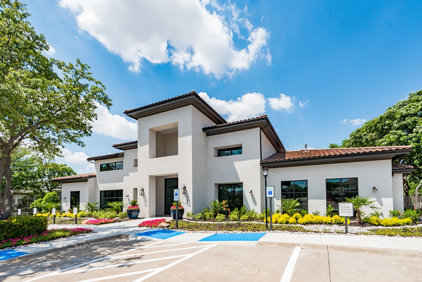 Elegant residential building surrounded by lush landscaping and clear blue skies, showcasing modern architecture with clean lines and large windows.