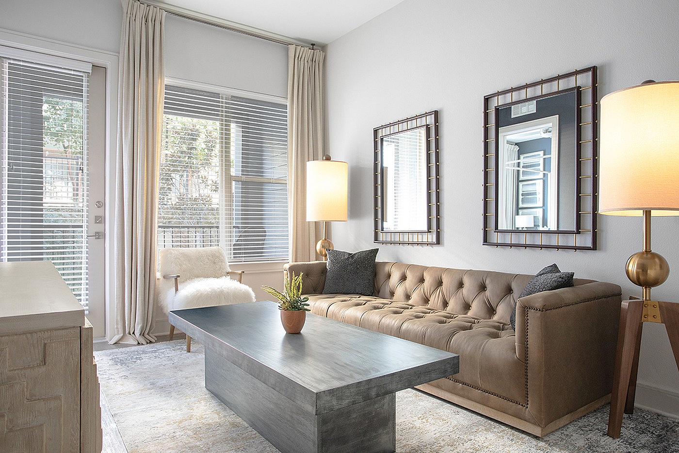 Elegant living room with a plush tufted leather sofa, modern coffee table, and floor-to-ceiling windows allowing natural light to flood the room.