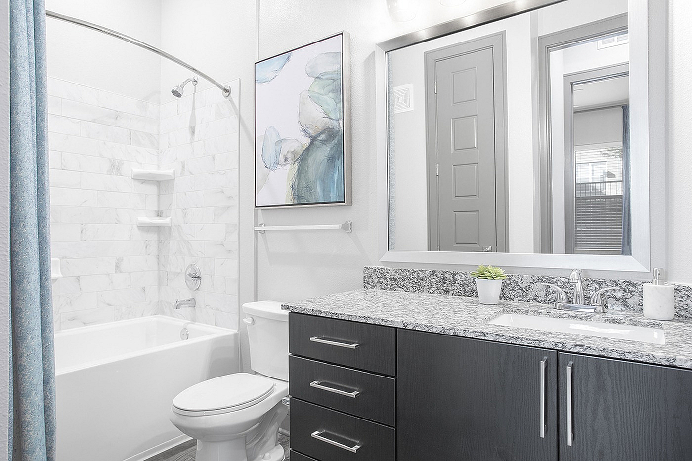 Elegant bathroom featuring a marble-tiled shower, modern vanity with granite countertop, and stylish decor.