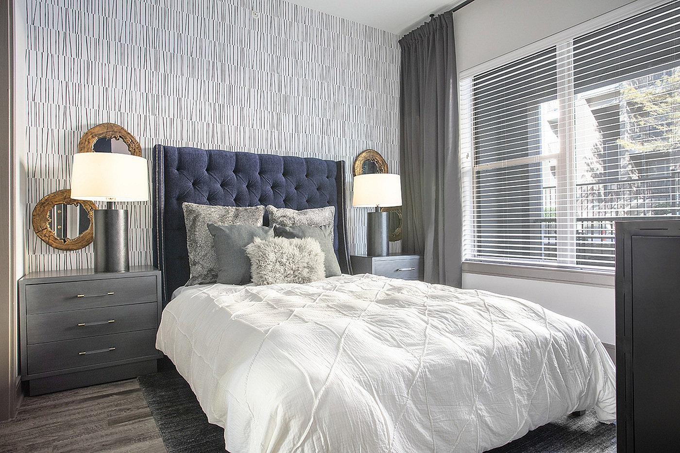Elegant bedroom with plush navy headboard, cozy pillows, and abundant natural light.