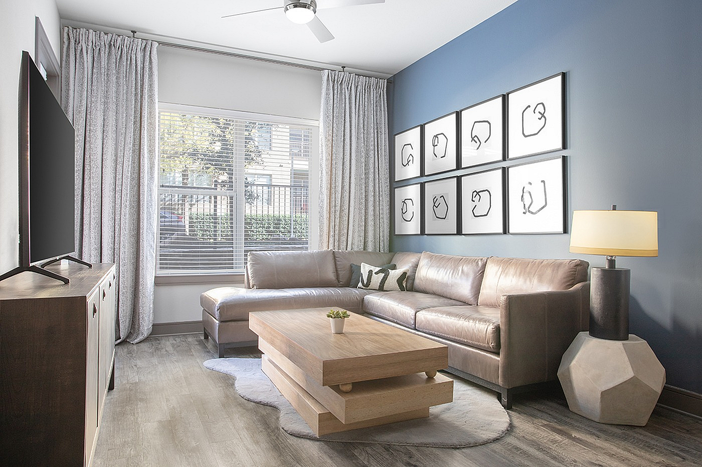 Modern living room with chic leather sectional, geometric coffee table, and elegant framed art on a stylish blue accent wall.