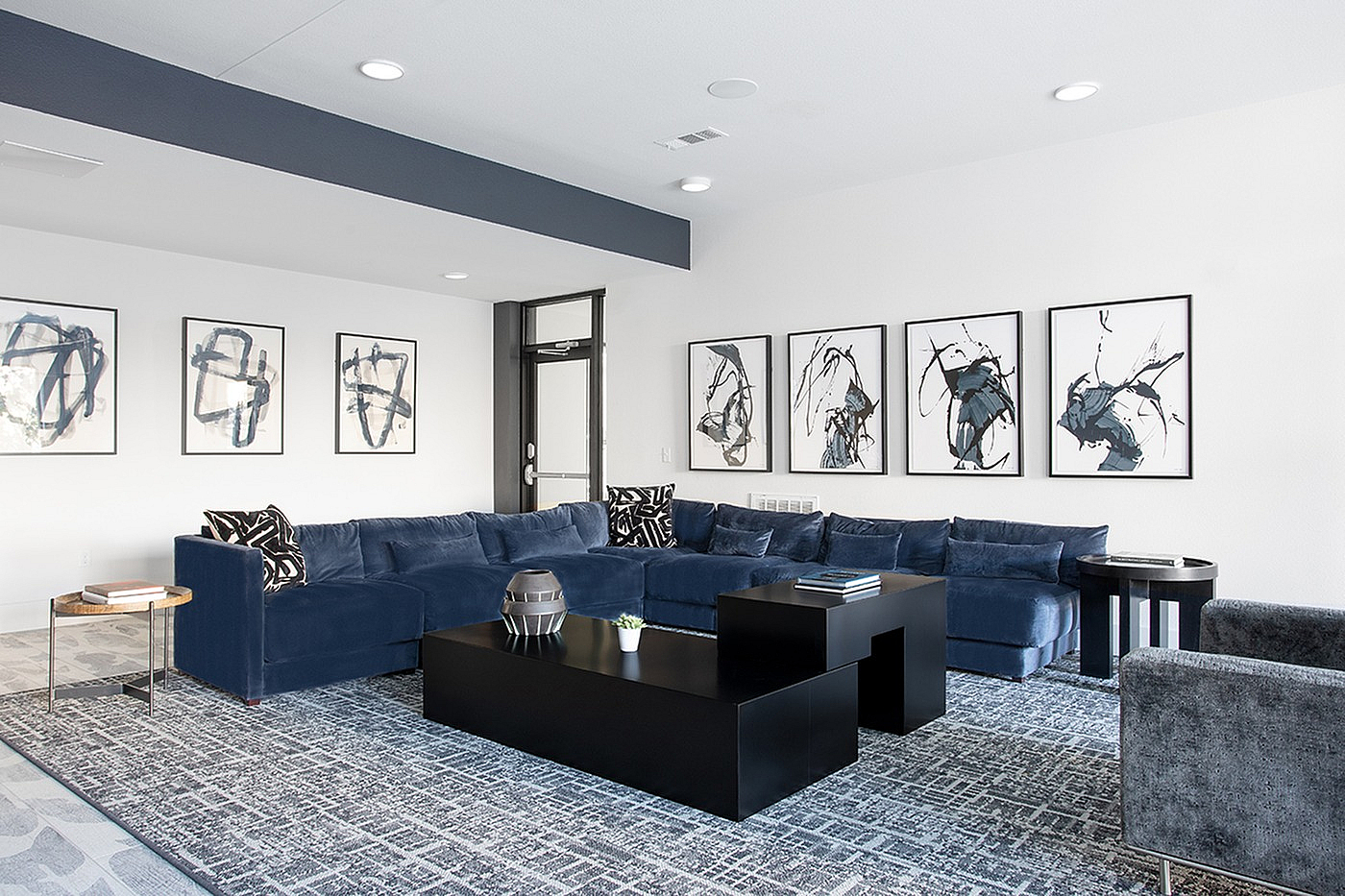 Sophisticated living room with plush navy sectional, modern art pieces, and contemporary black coffee table.