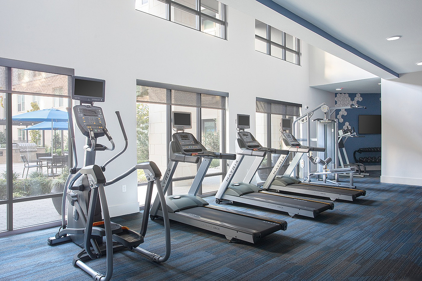 Modern gym with state-of-the-art treadmills and elliptical machines, stylish interior design, and large windows for natural light.
