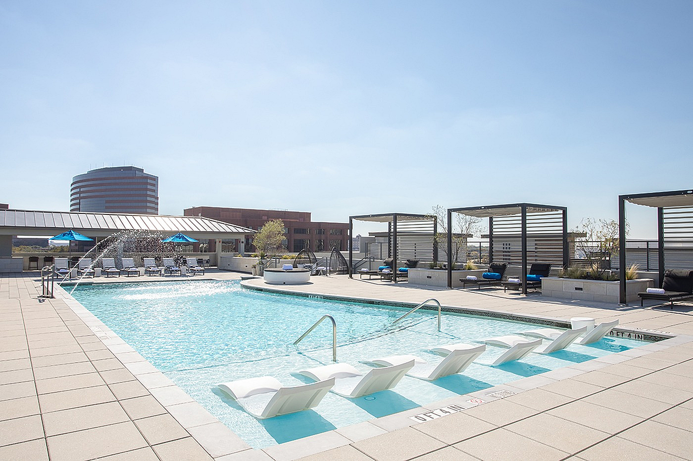 Luxurious rooftop pool with stylish lounge chairs, shaded cabanas, and stunning city views for ultimate relaxation.