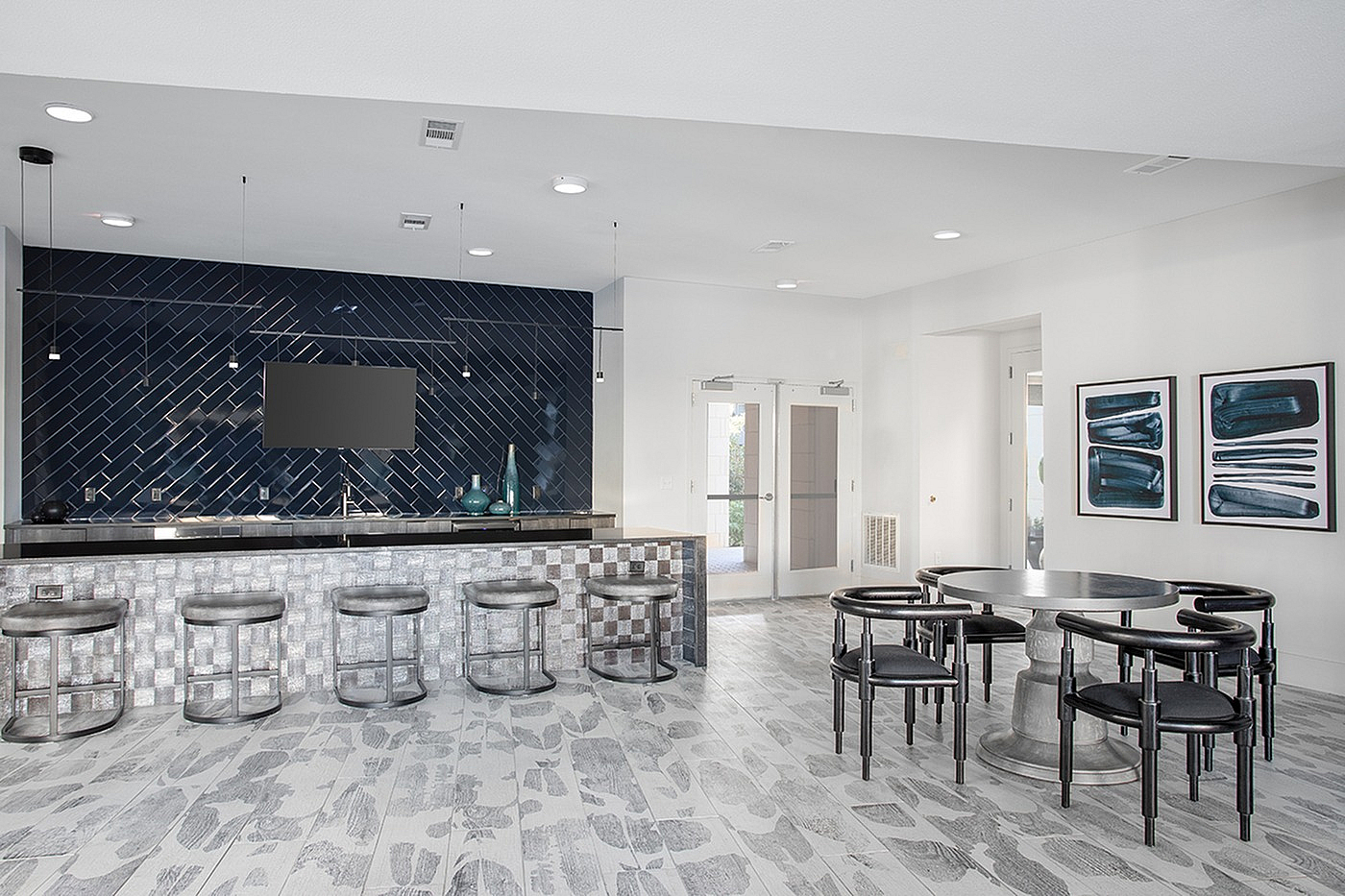 Modern communal dining area featuring a sleek black and silver design with a chic tiled bar and contemporary artwork.