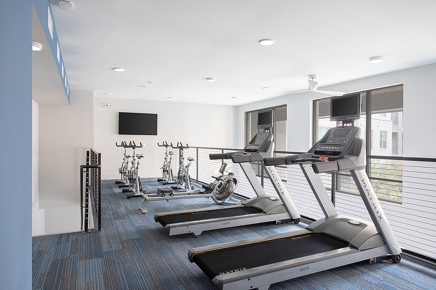 Bright and modern apartment gym featuring state-of-the-art treadmills and stationary bikes in a spacious, well-lit environment.