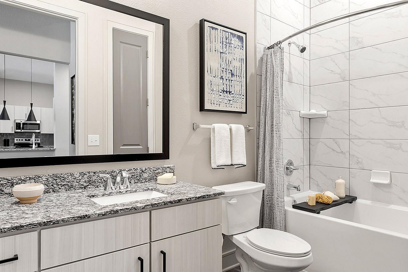 Elegant bathroom with chic granite countertop, modern fixtures, and a stylish bathtub featuring a marble-patterned tile surround.