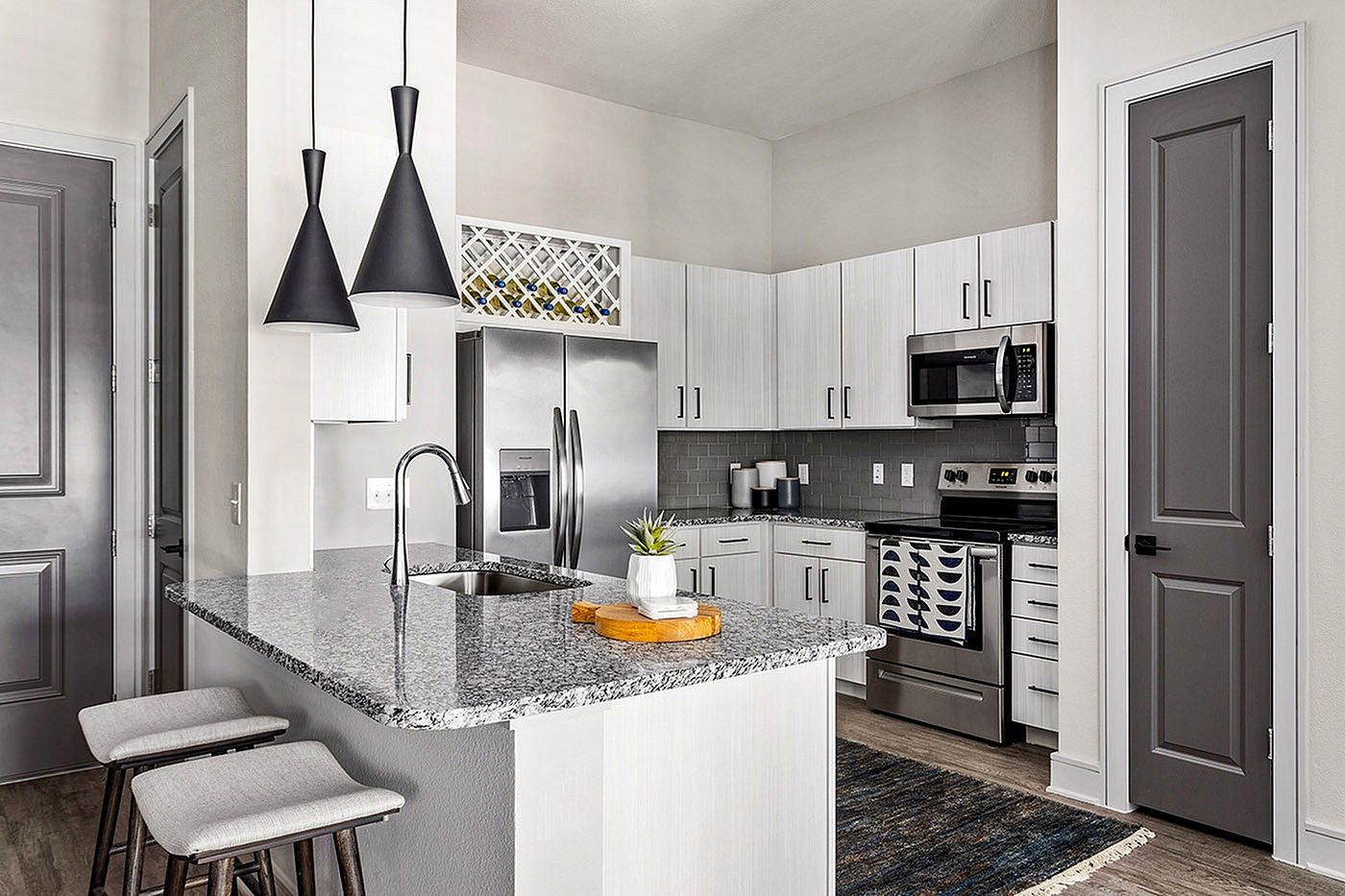 Modern kitchen with sleek granite countertops, stainless steel appliances, and chic pendant lighting, offering a stylish and functional space for culinary delights.