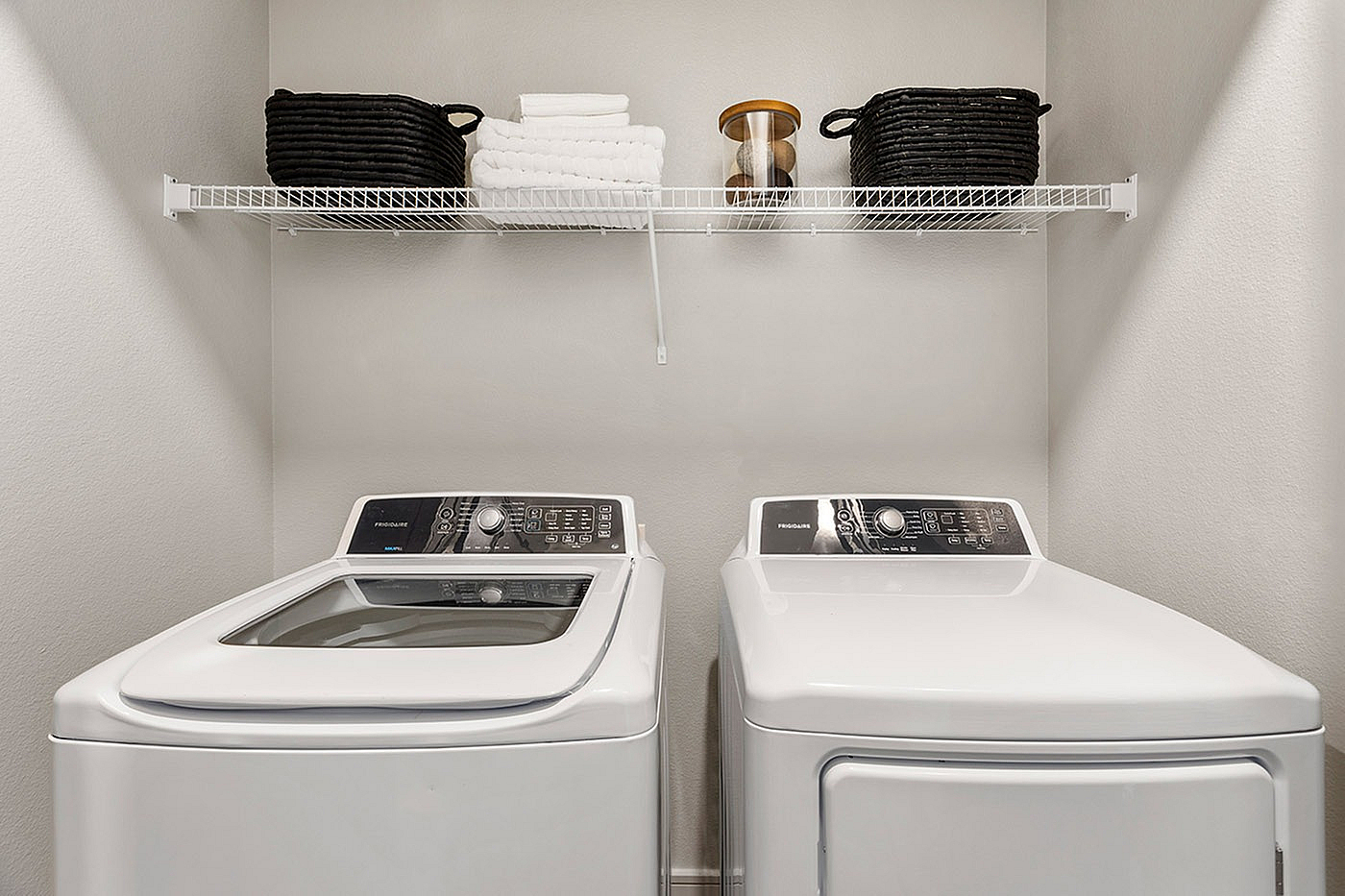 Modern laundry area with sleek washer and dryer, featuring organized shelving and stylish storage baskets.