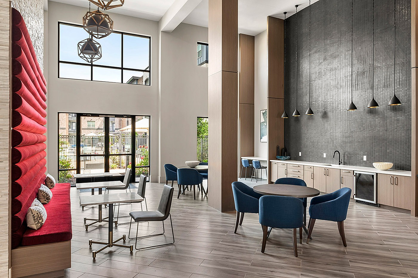 Chic modern apartment lounge with high ceilings, stylish blue seating, and an elegant kitchenette.