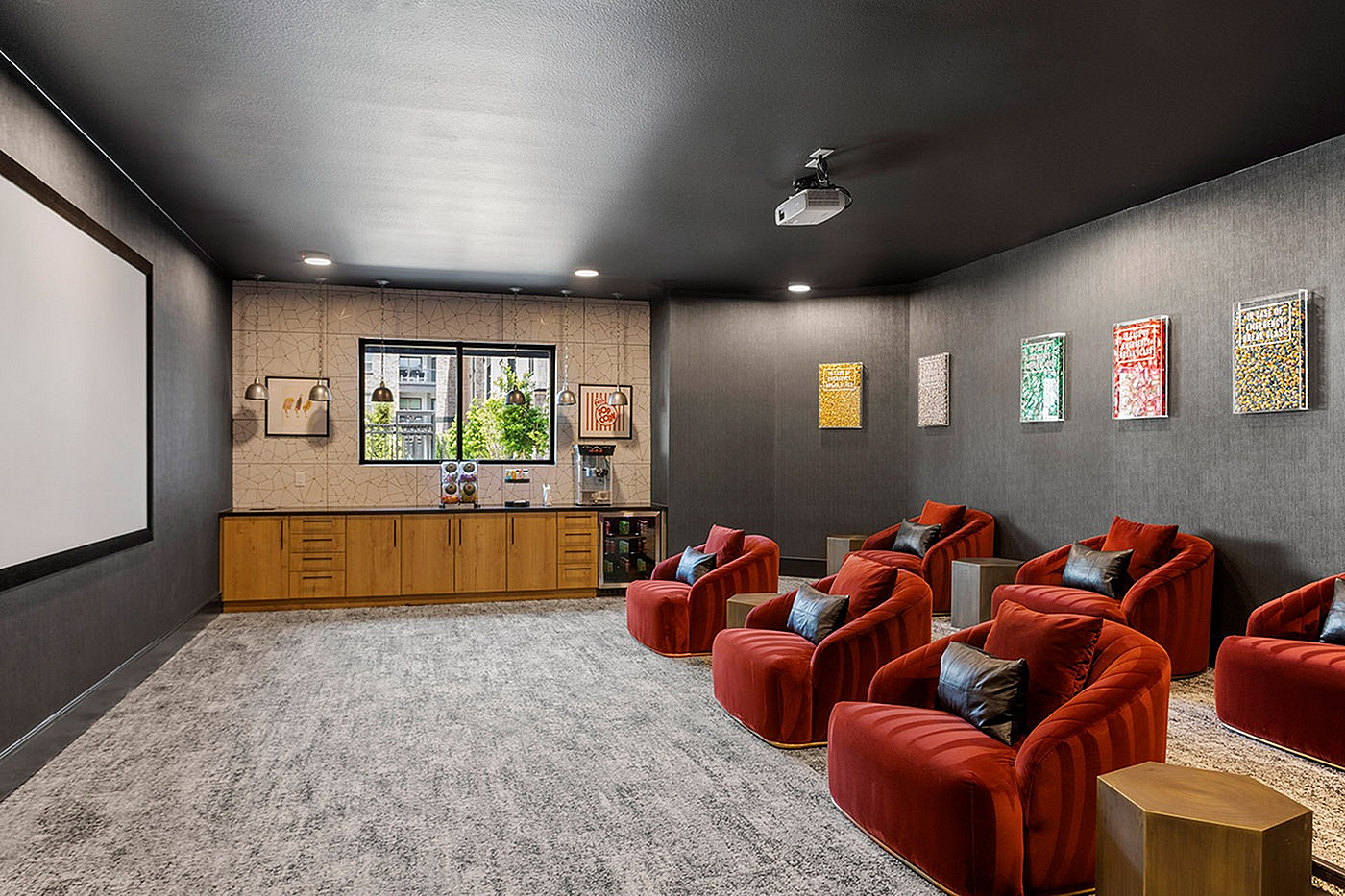 Luxurious home theater with plush red seating, modern decor, and a large projector screen for an ultimate cinematic experience.