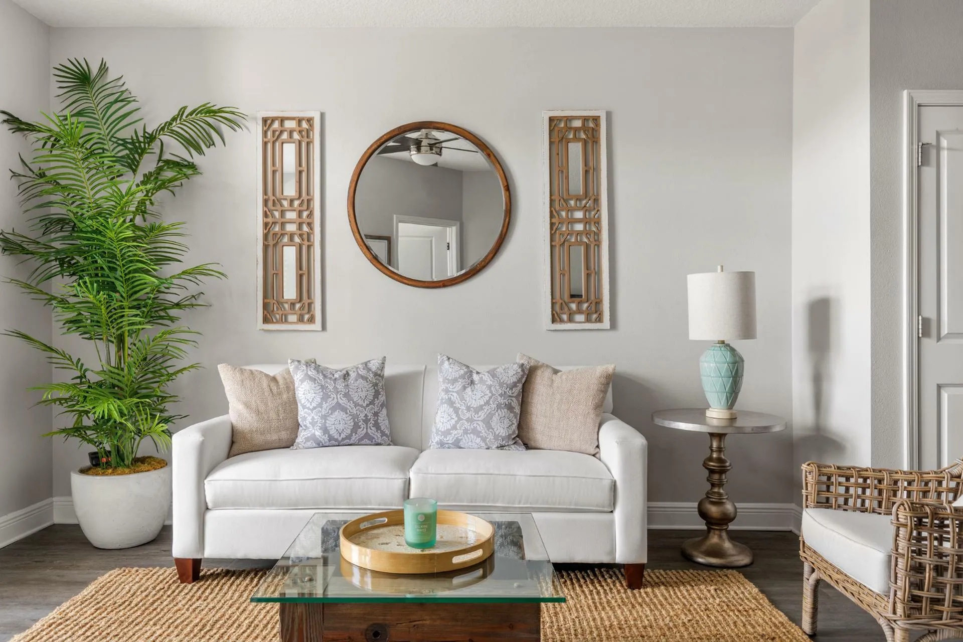 Chic living room with elegant white sofa, cozy pillows, stylish décor, and a lush green plant creating a welcoming ambiance.