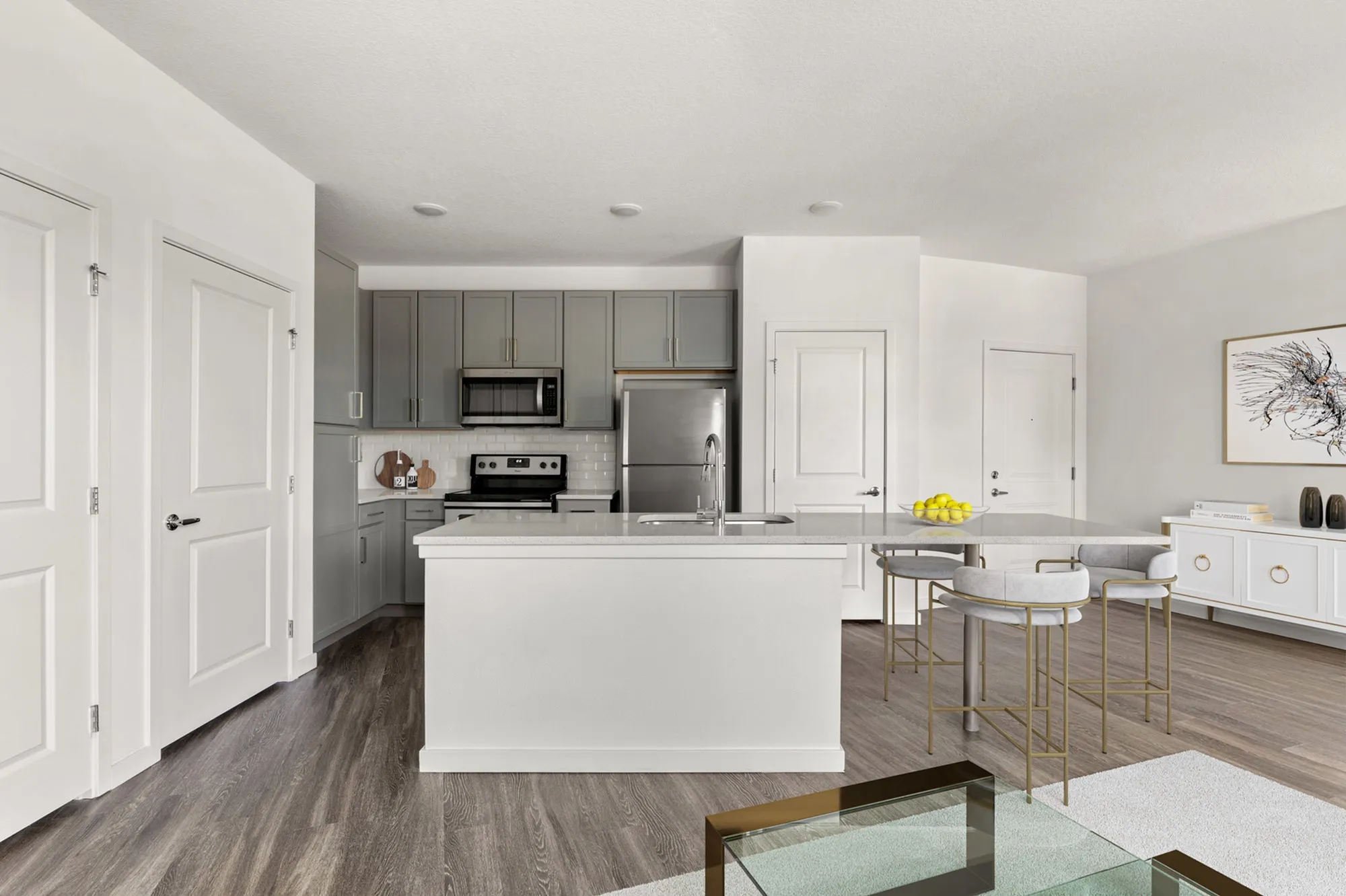 Furnished kitchen with extended kitchen island, stainless steel appliances, built in pantry, and light gray cabinets