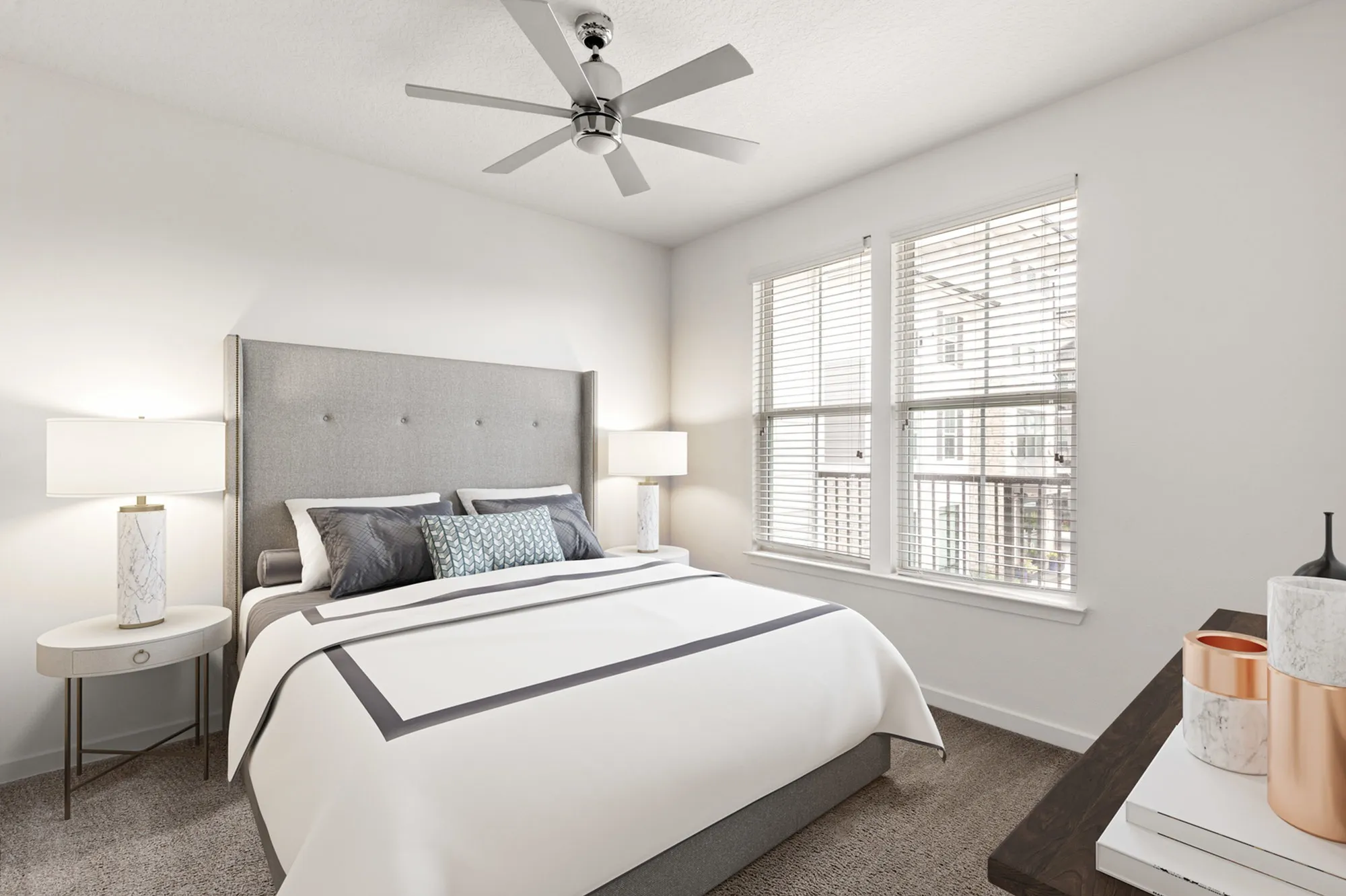 Furnished bedroom with lighted ceiling fan, two windows and bedside tables with lamps