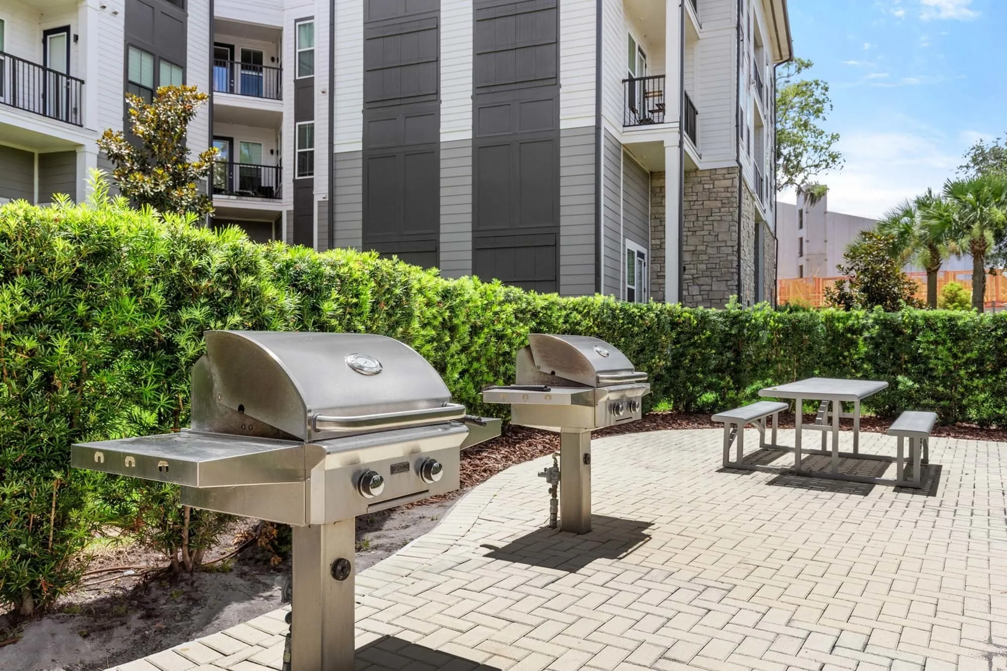 Two Stainless steel grill outdoors on a patio area with a picnic table