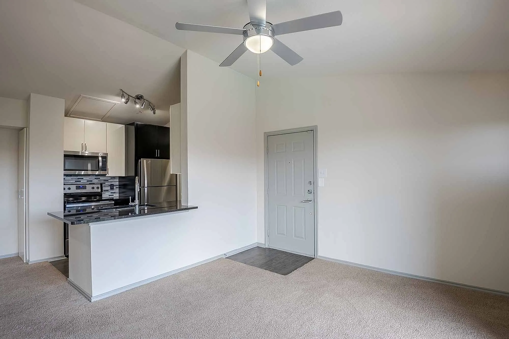 Modern apartment with sleek stainless steel kitchen, stylish ceiling fan, and inviting open layout.