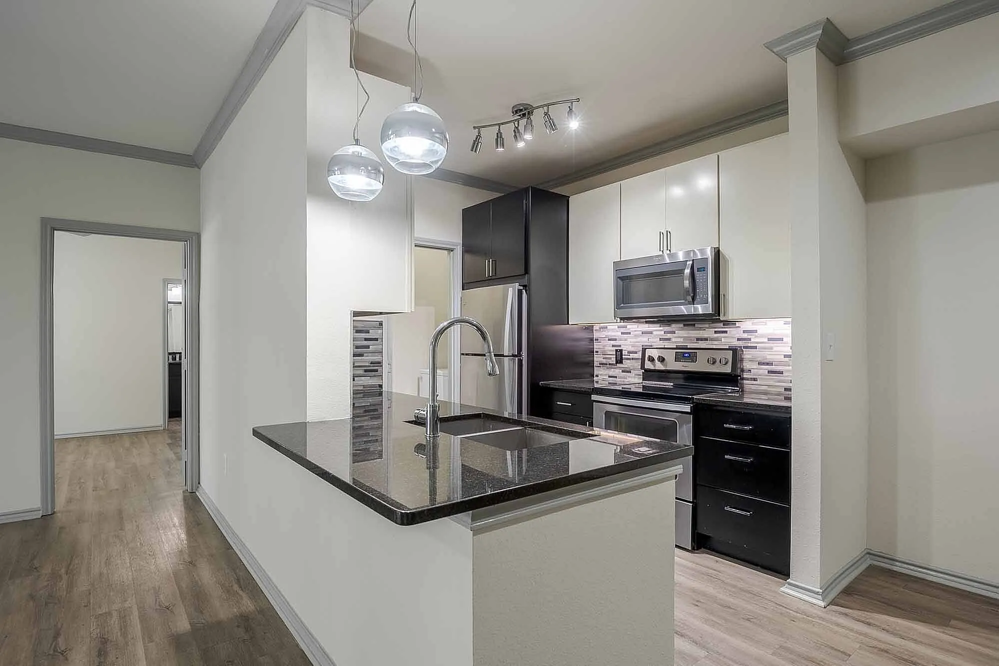 Modern kitchen with sleek granite countertops, stainless steel appliances, and elegant pendant lighting.