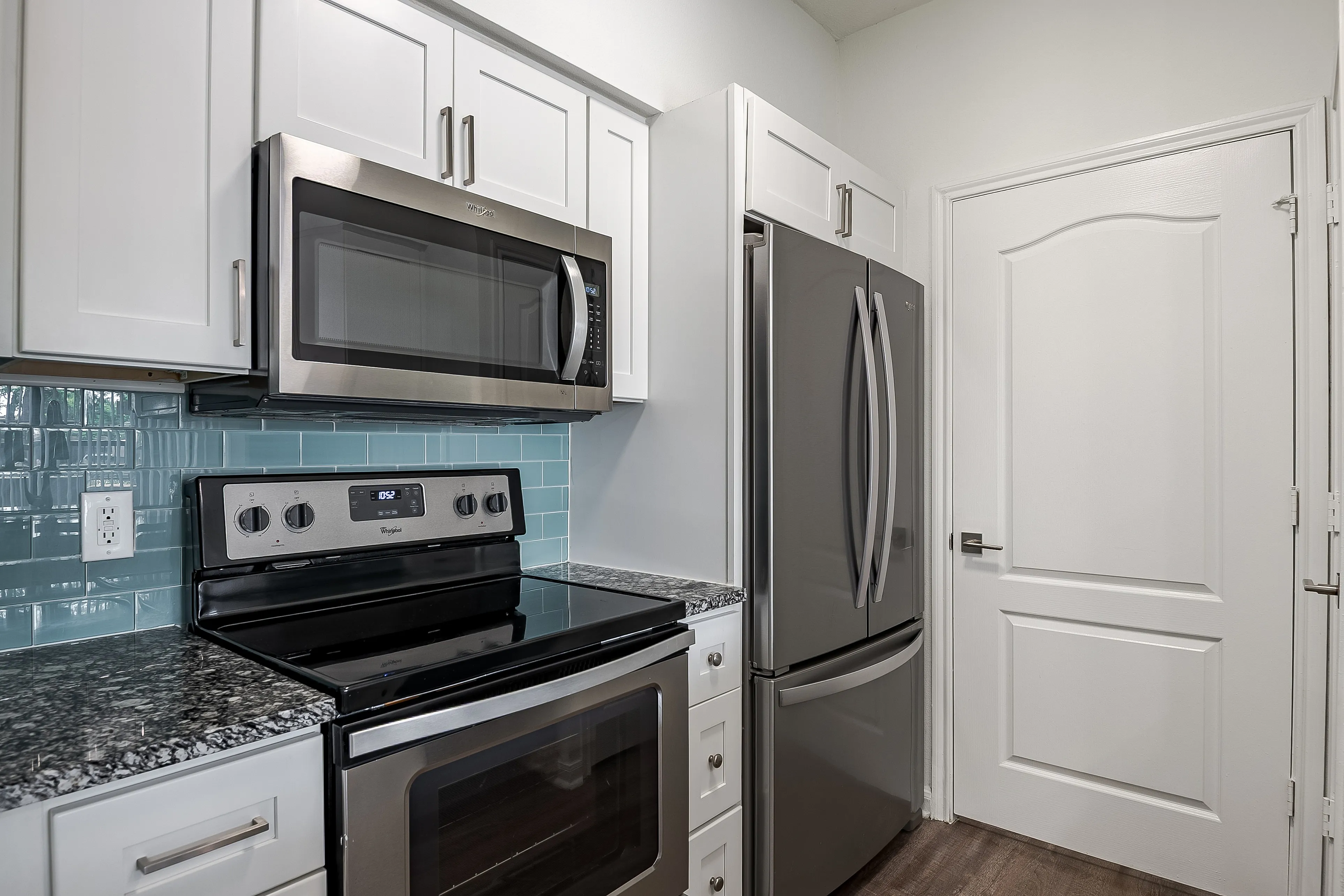 Modern kitchen with stainless steel appliances, sleek granite countertops, and stylish white cabinetry.