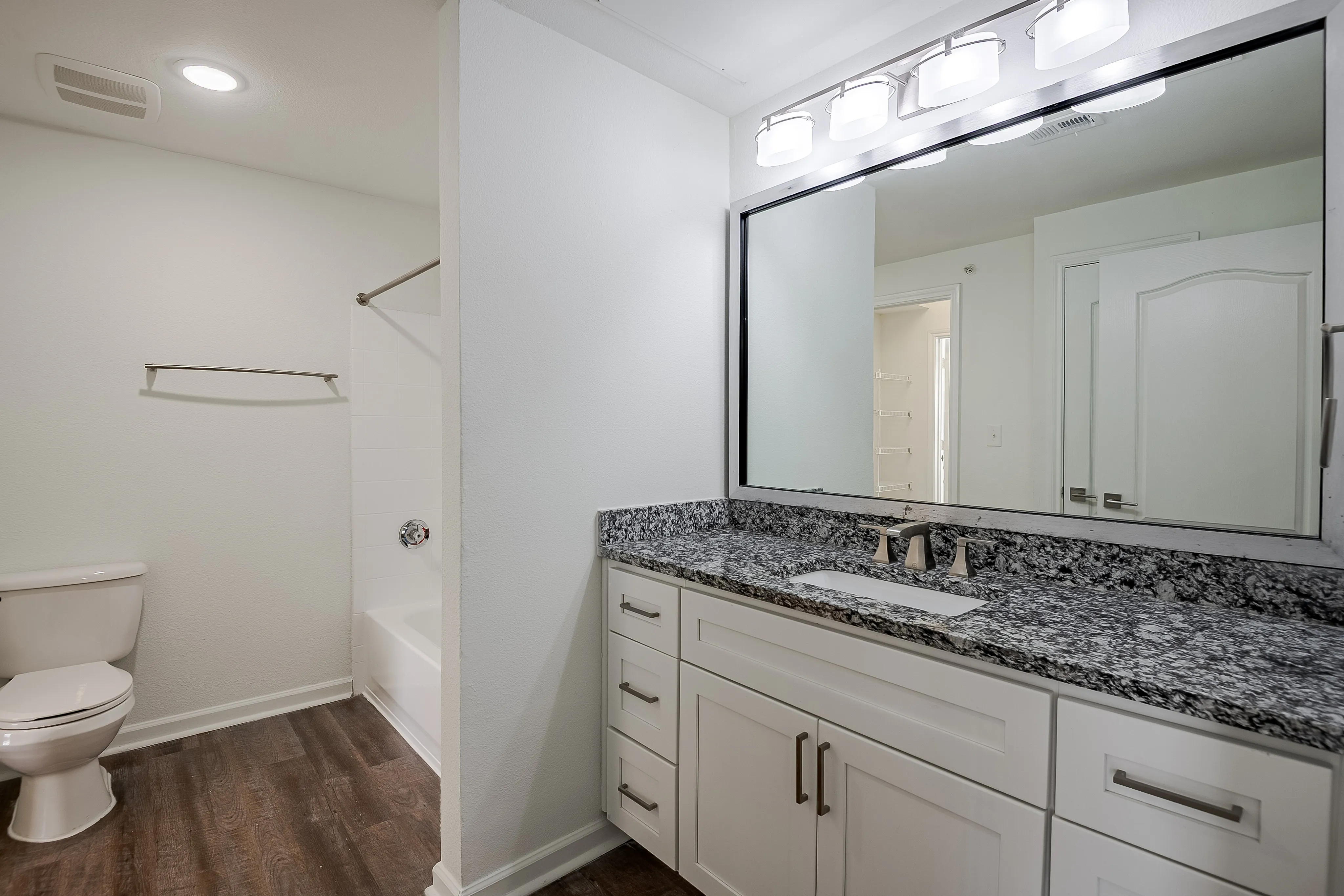 Modern bathroom featuring elegant granite countertops, soft lighting, and sleek fixtures with a spacious vanity area.