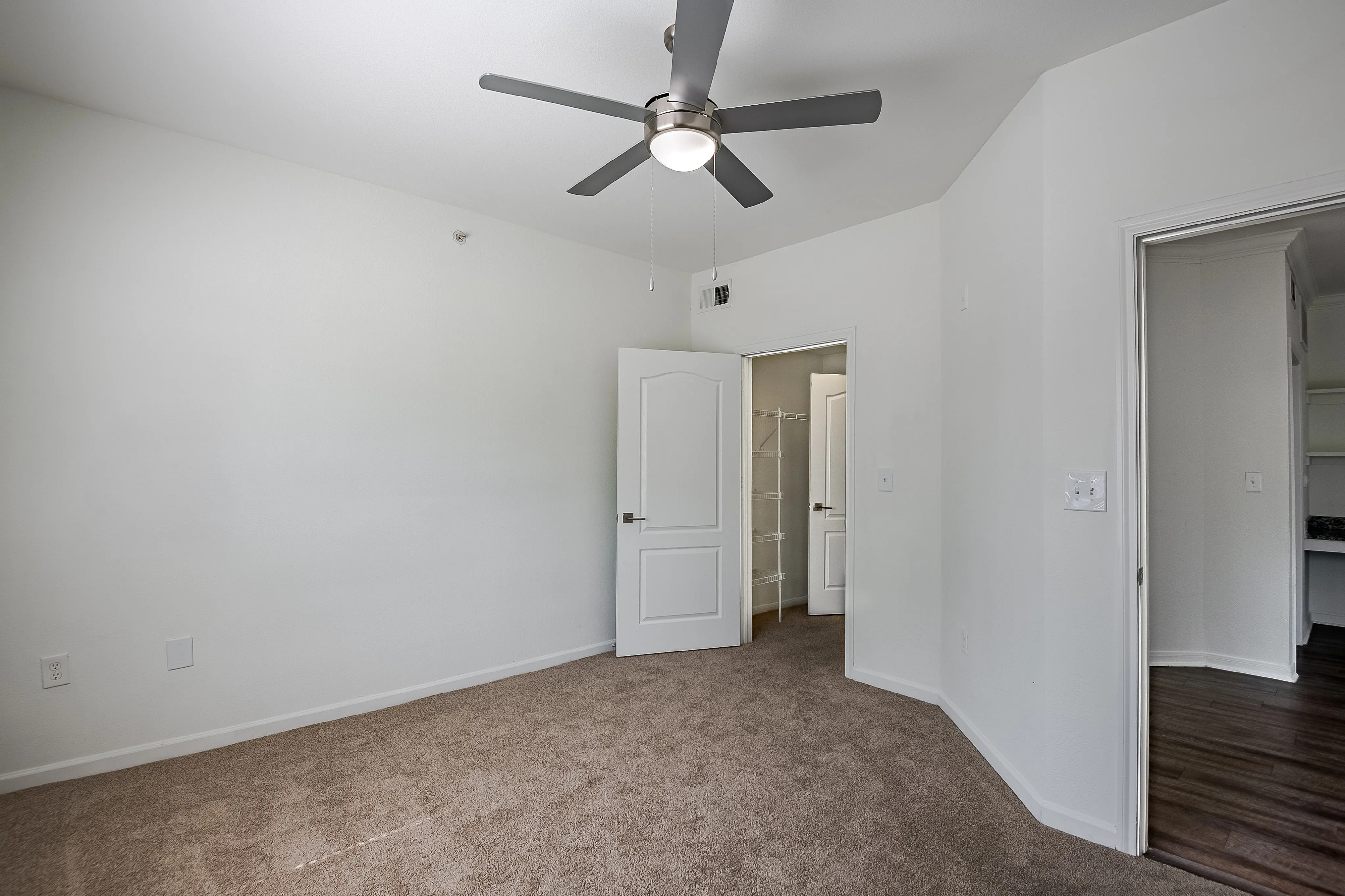 Bright and spacious bedroom with ceiling fan and walk-in closet, perfect for modern living.