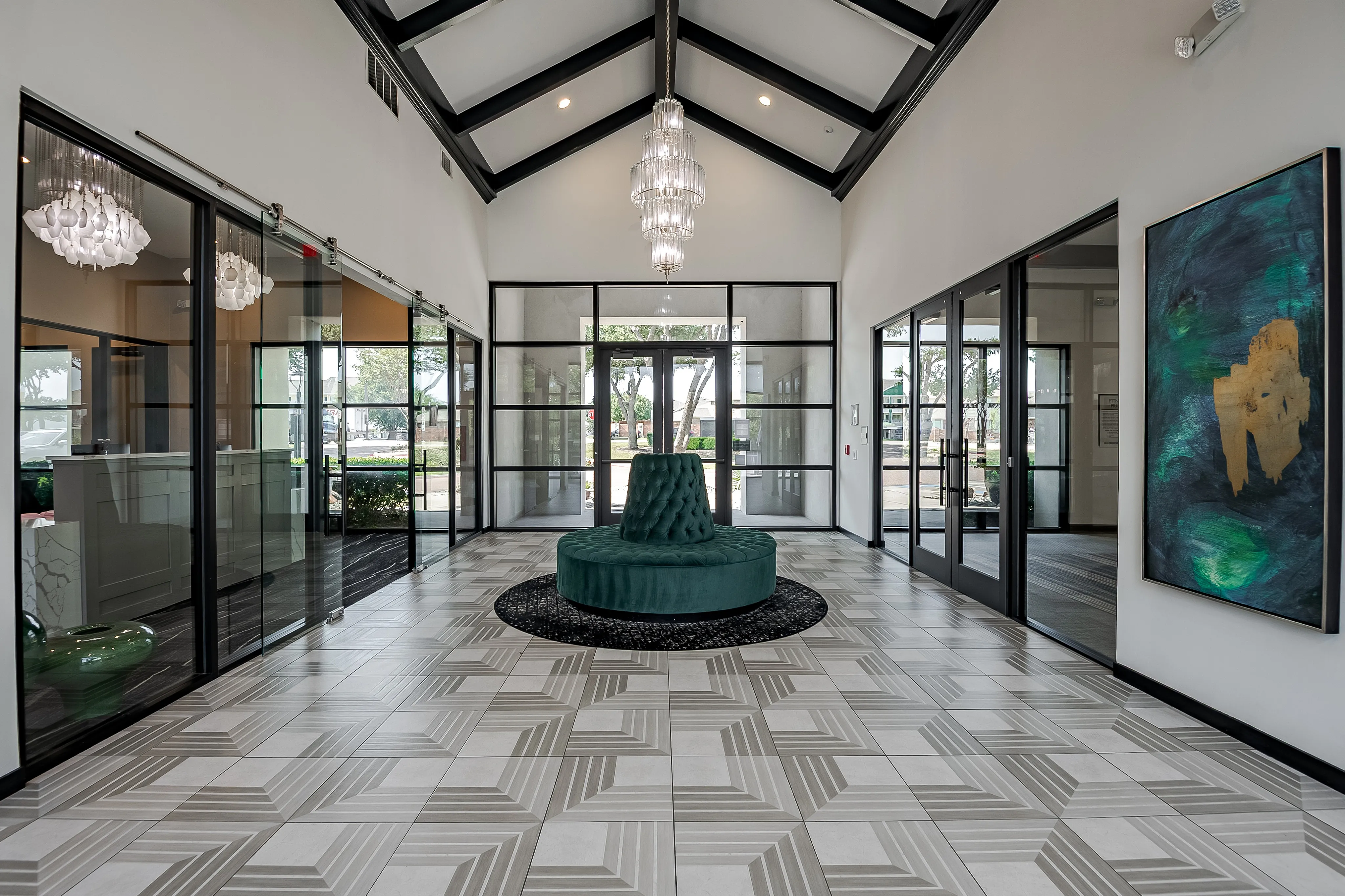 Elegant lobby featuring modern glass doors, geometric tiled flooring, and a luxurious chandelier.