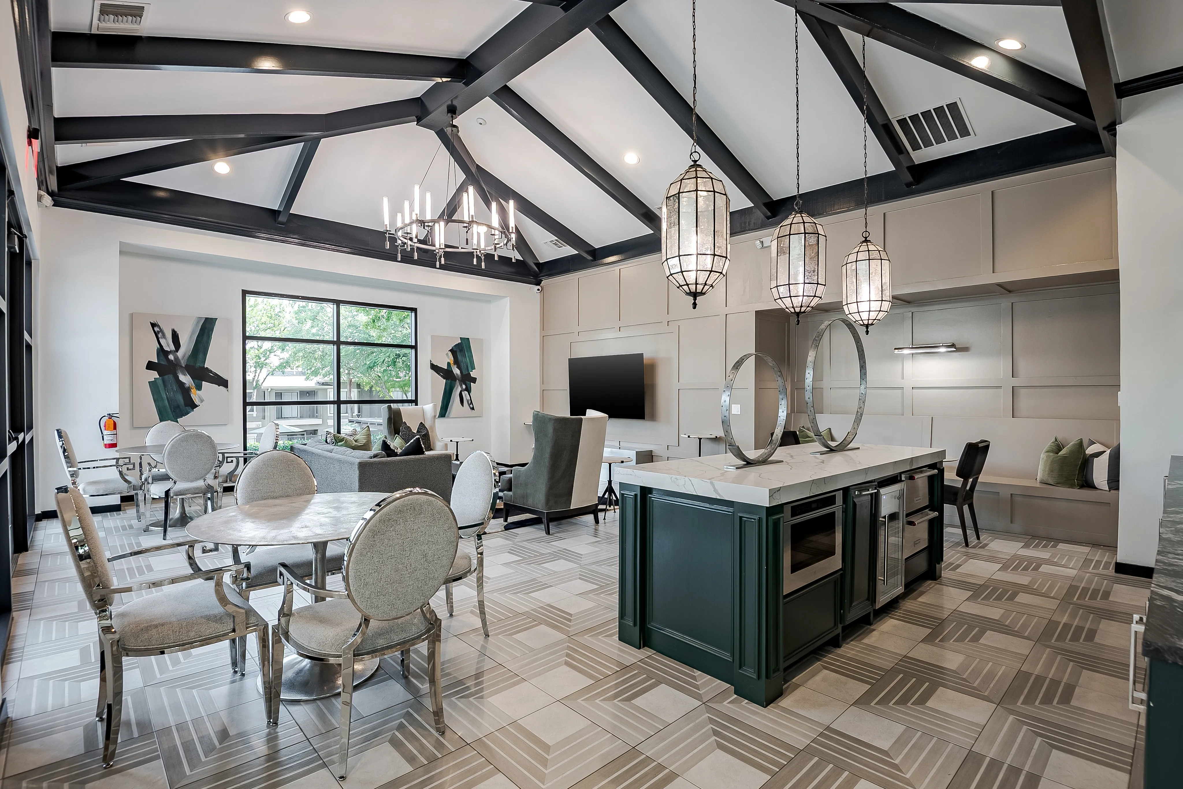 Elegant living area with vaulted ceilings, stylish chandeliers, and modern furnishings, featuring a spacious kitchen island and cozy seating arrangement.