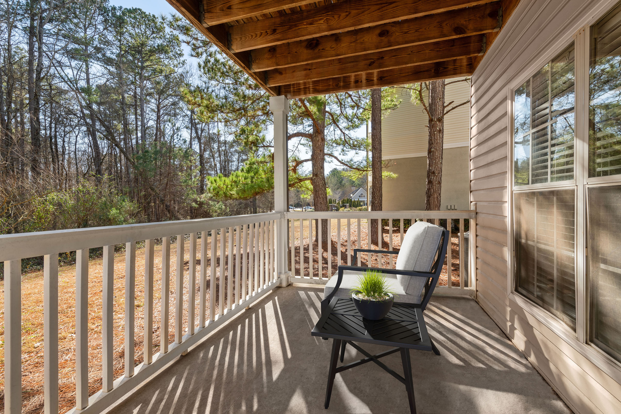 Charming outdoor balcony with cozy seating, surrounded by serene wooded views, perfect for relaxation.